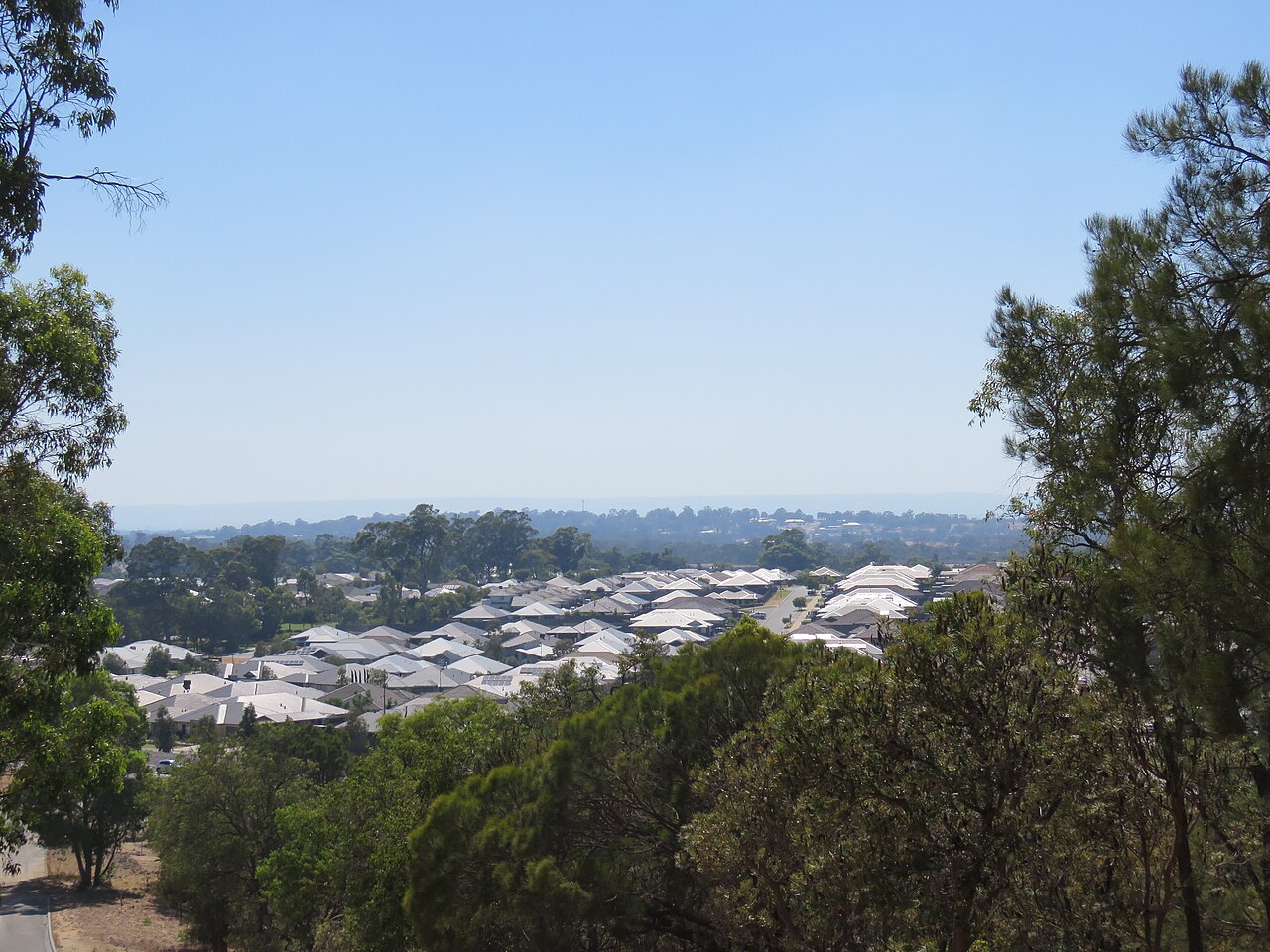 Baldivis, WA, Residential rooftops surrounded by trees under clear sky
