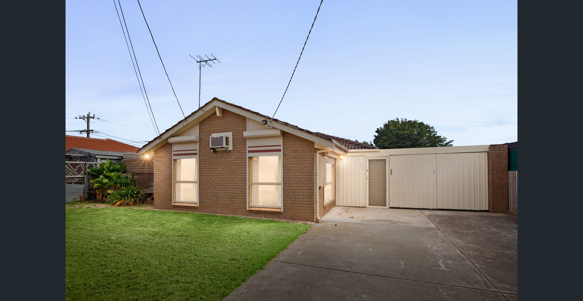 An established detached brick home with a tiled roof, front lawn and a driveway beside the house. 223 Shaws Road, Werribee, VIC.